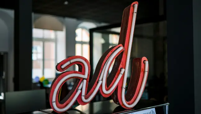 Red neon 'ad' sign in a dim office interior.